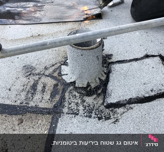 אדם משתמש במבער לאיטום גג עם יריעות ביטומניות